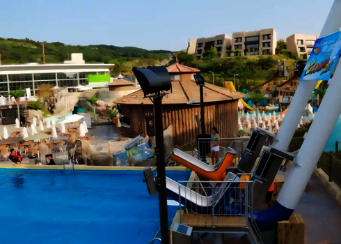 Ein gelber und ein blauer Cannonball in einem Wasserpark, die vor einem blauen Schwimmbecken stehen.
