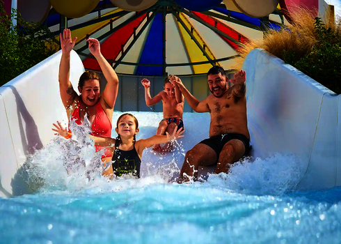 Eine Familie rutscht gemeinsam lachend durch den Wildwasserfluss.