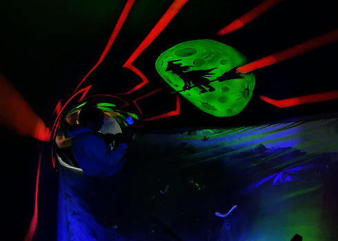 Zwei Personen montieren UV-Grafiken mit Hexe und Mond in einer Röhrenrutsche.