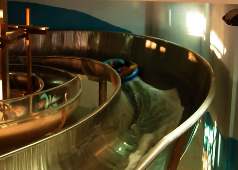 Blick von hinten auf eine Person im Rutschreifen in einem Crazy River aus Edelstahl.