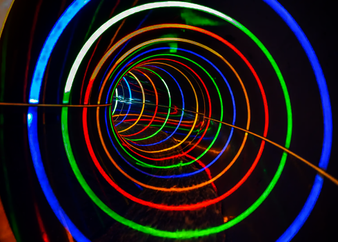 Eine dunkle Wasserrutsche von innen mit Lichteffekten in bunten Farben.