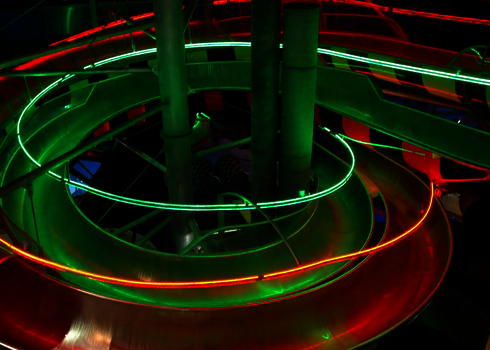 Verschlungene Body Racer Rutschen mit LED-Leuchten und Schachbrettmuster von oben.