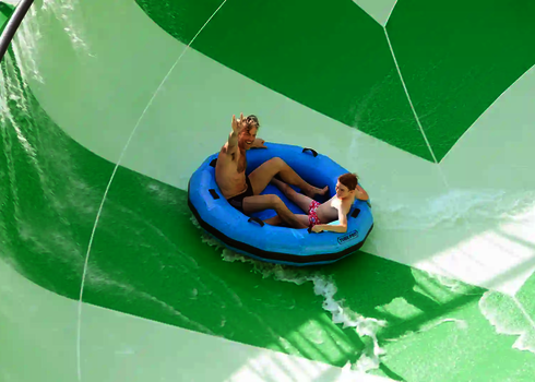 Vater und Sohn rutschen auf blauem Rutschreifen die Lotus Reifenrutsche hinab.