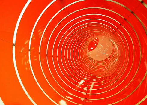 Innenansicht einer orangefarbenen Röhrenrutsche mit Tageslichteffekten.