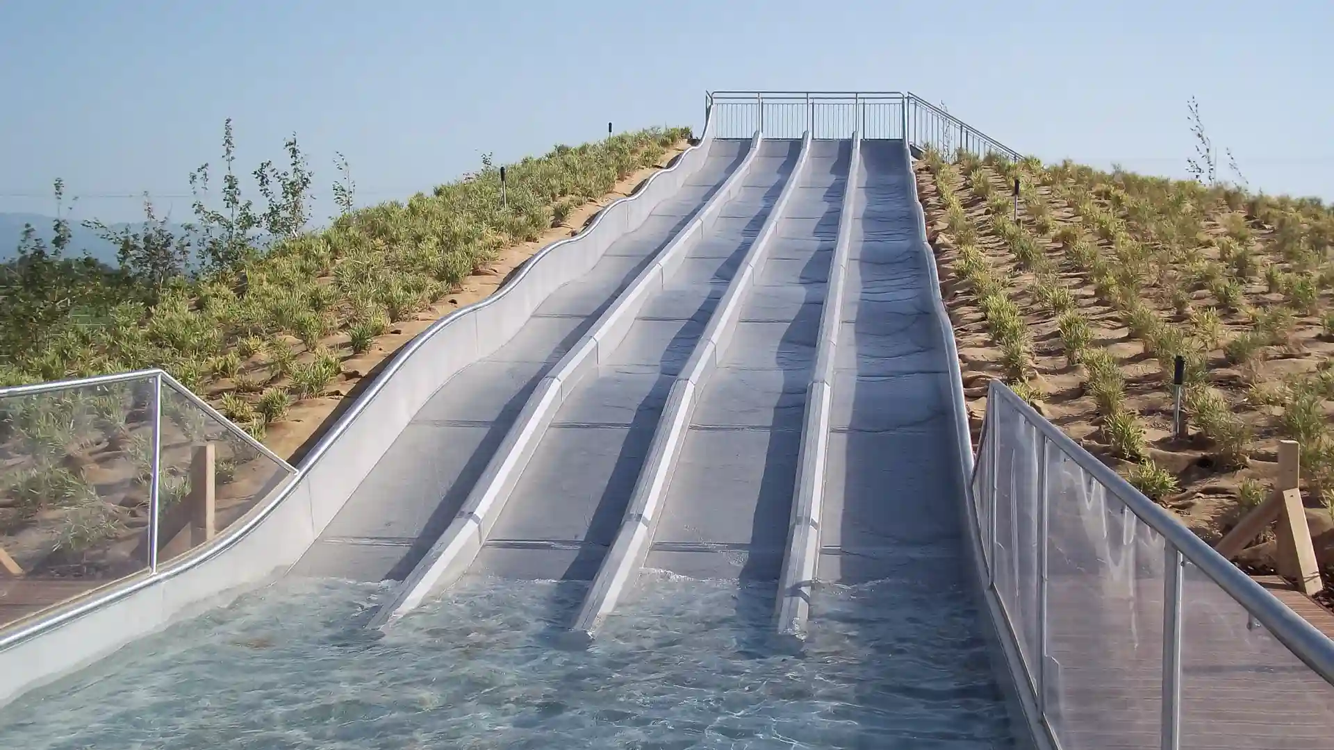 Leere, mehrspurige Multilane im Freibad führt gerade ins Wasserbecken.